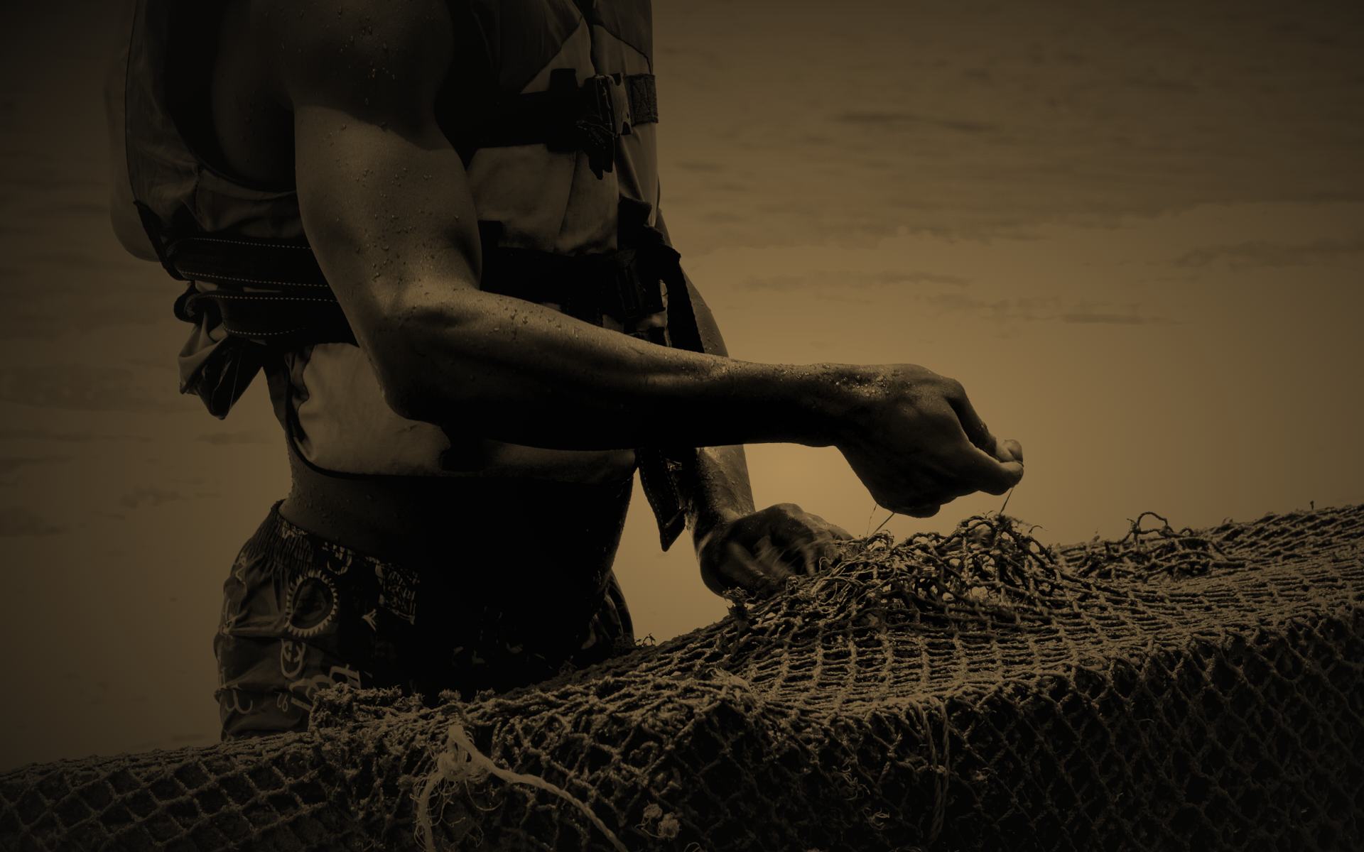 Manos de un pescador remendando una red
